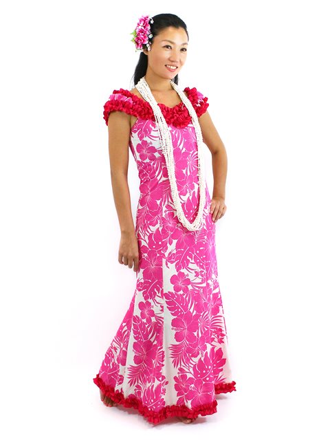 A woman wearing a traditional Hawaiian muumuu dress in pink with a hibiscus pattern and ruffle details, accessorized with a floral headpiece and a white beaded necklace.