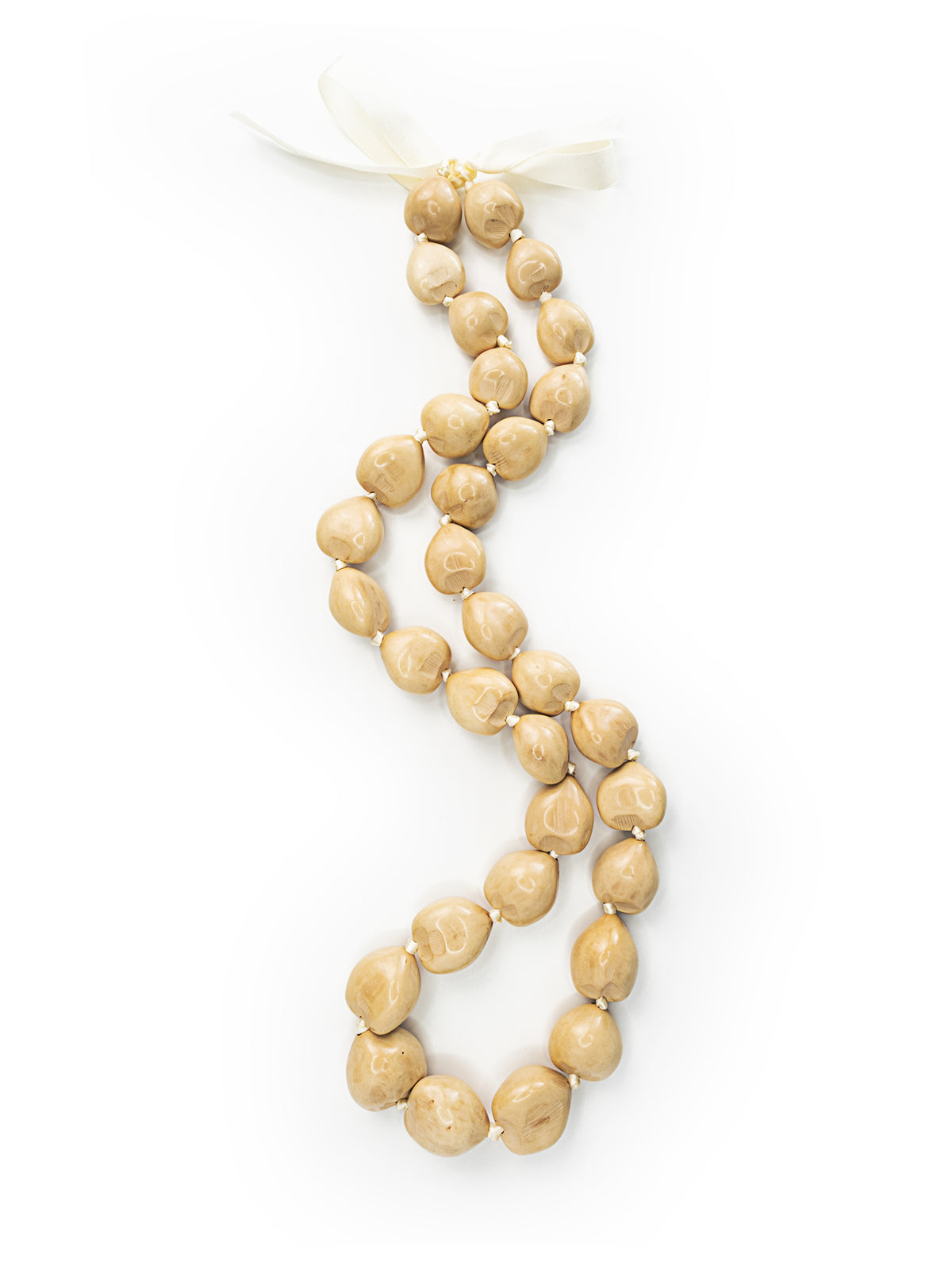 A natural kukui nut lei with glossy-painted white nuts against a white background.